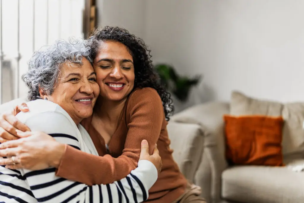 Senior mother and daughter hug on couch