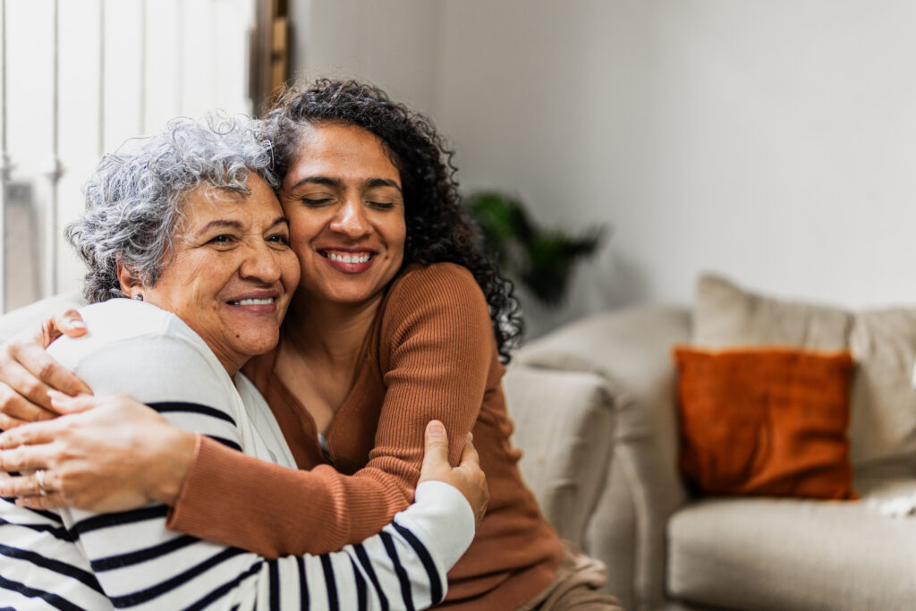 Senior mother and daughter hug on couch